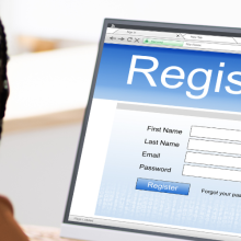 woman at computer with screen that reads "Register"