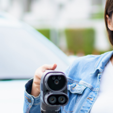 woman holding an electric vehicle charger while giving a thumbs up