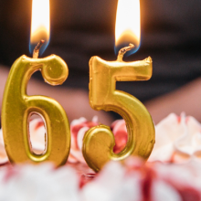 birthday cake with large "6" and "5" candles on it.
