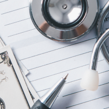 photo of health insurance form, calculator, money, and stethoscope on a real desktop