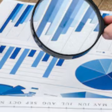 hand with magnifying glass examining financial report