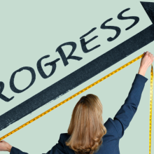 woman holding tape measure and measuring an upward pointing line with "progress" above it
