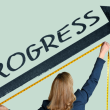 woman measuring "progress" with tape measure