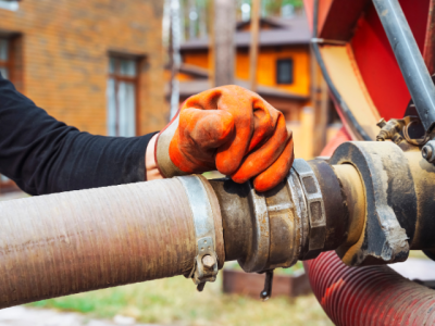 a hand connects a hose to a sewage tanker truck