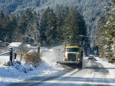 diesel truck plowing snow on rural road 