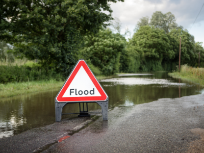 water covering road with warning sign reading "flood"