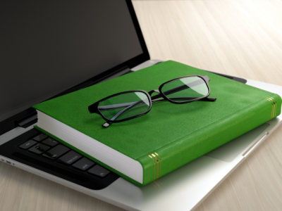 photo of a generic green book and eyeglasses on a laptop keyboard