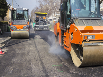 photo of three vehicles being used to re-pave a local road 