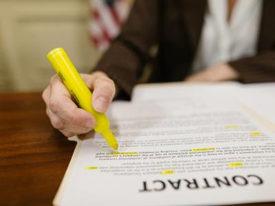 contract on table with person holding highlighter