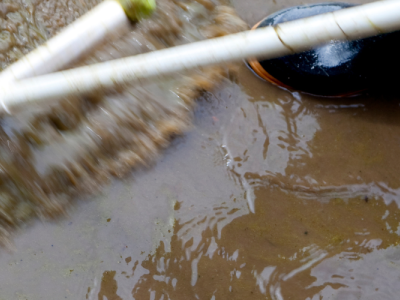 photo of unseen person in waterpfoof boots using squeegee to move flood water