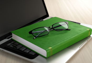 photo of a generic green book and eyeglasses on a laptop keyboard