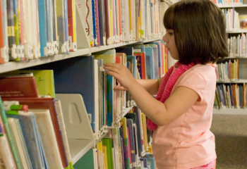 Young girl browsing shelves for library books