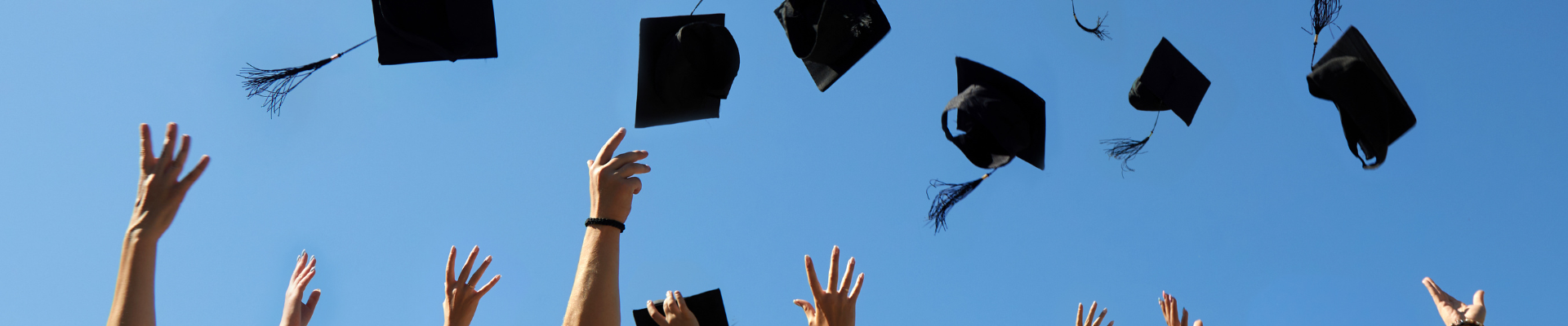 photo of graduates' hands throwing mortarboard caps