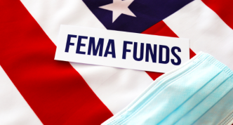 sign reading "FEMA Funds" with american flag in background